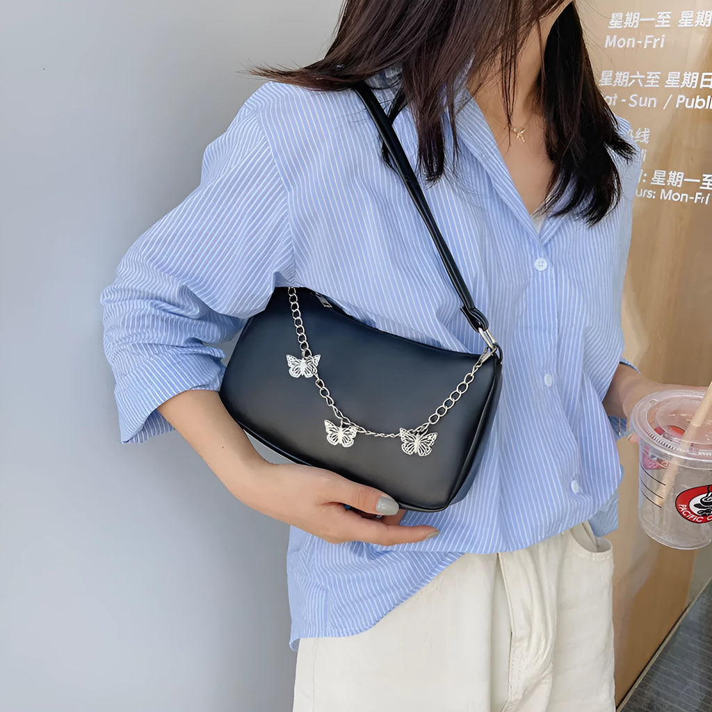 Retro-style light blue underarm shoulder bag with a silver butterfly chain strap, shown worn crossbody.
