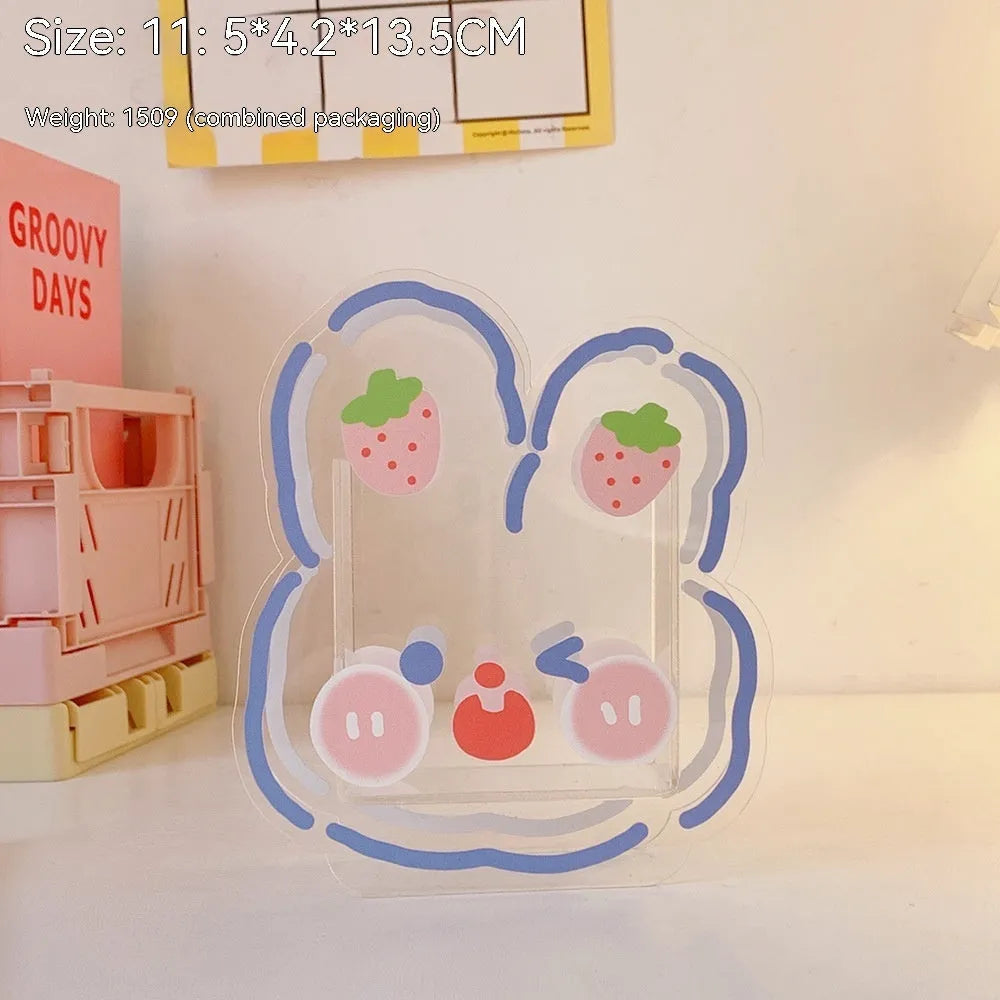 Clear square acrylic storage box with a colourful printed lid featuring a cute design, shown holding pens and stationery.