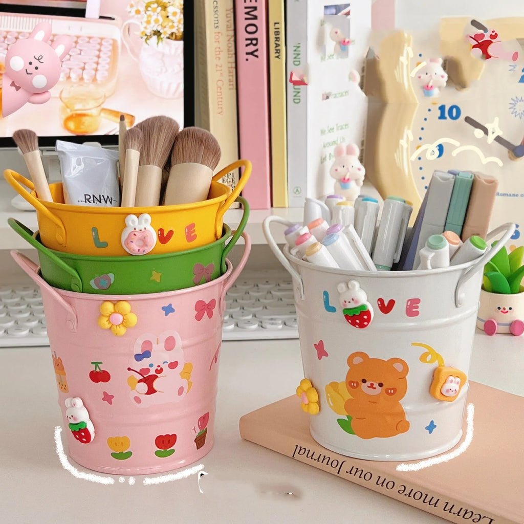 Round metal pen holder in pink with creative iron art design on a wooden desk.