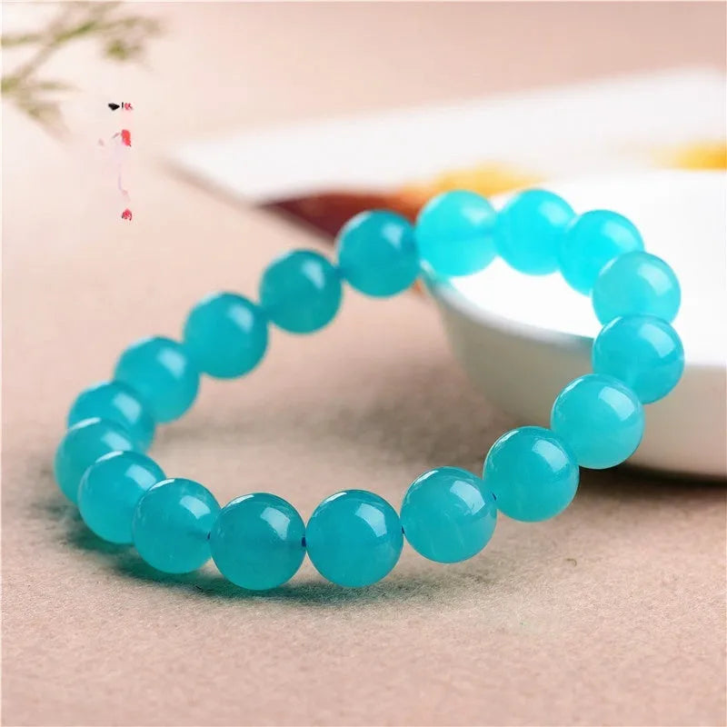 Natural blue-green Grade 7A Amazonite scattered beads in various sizes next to a finished crystal bracelet.