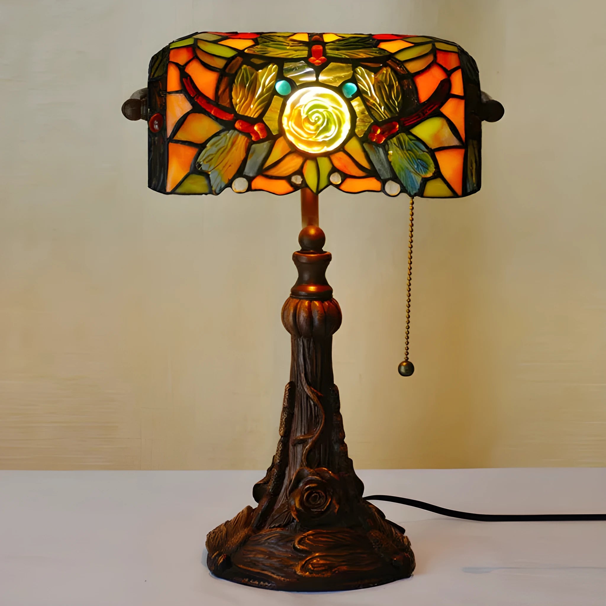 Tiffany style table lamp with colourful stained glass shade and resin base on a wooden desk