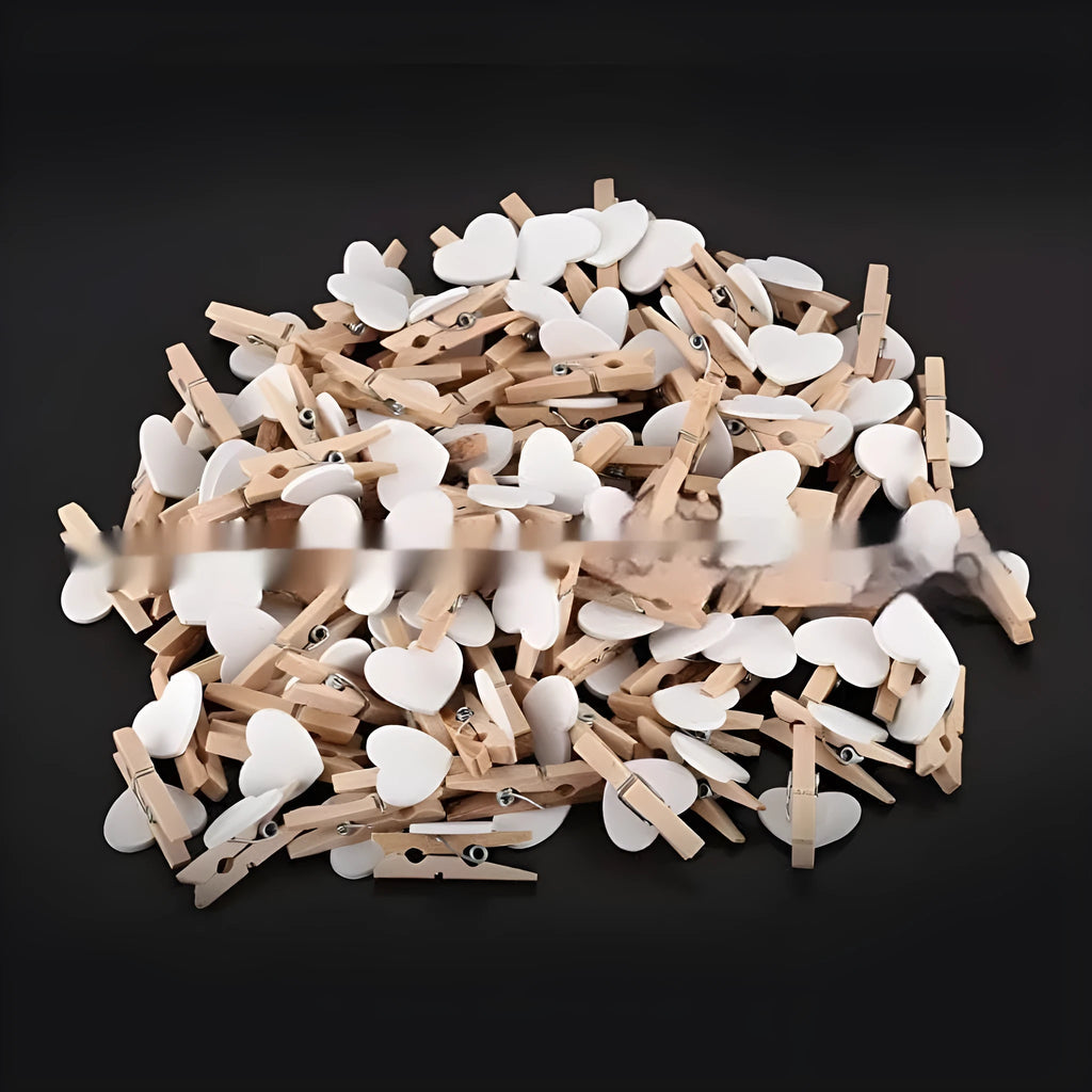 Set of five colourful handmade wooden heart-shaped clips in red, pink, white, and yellow on a wooden surface.