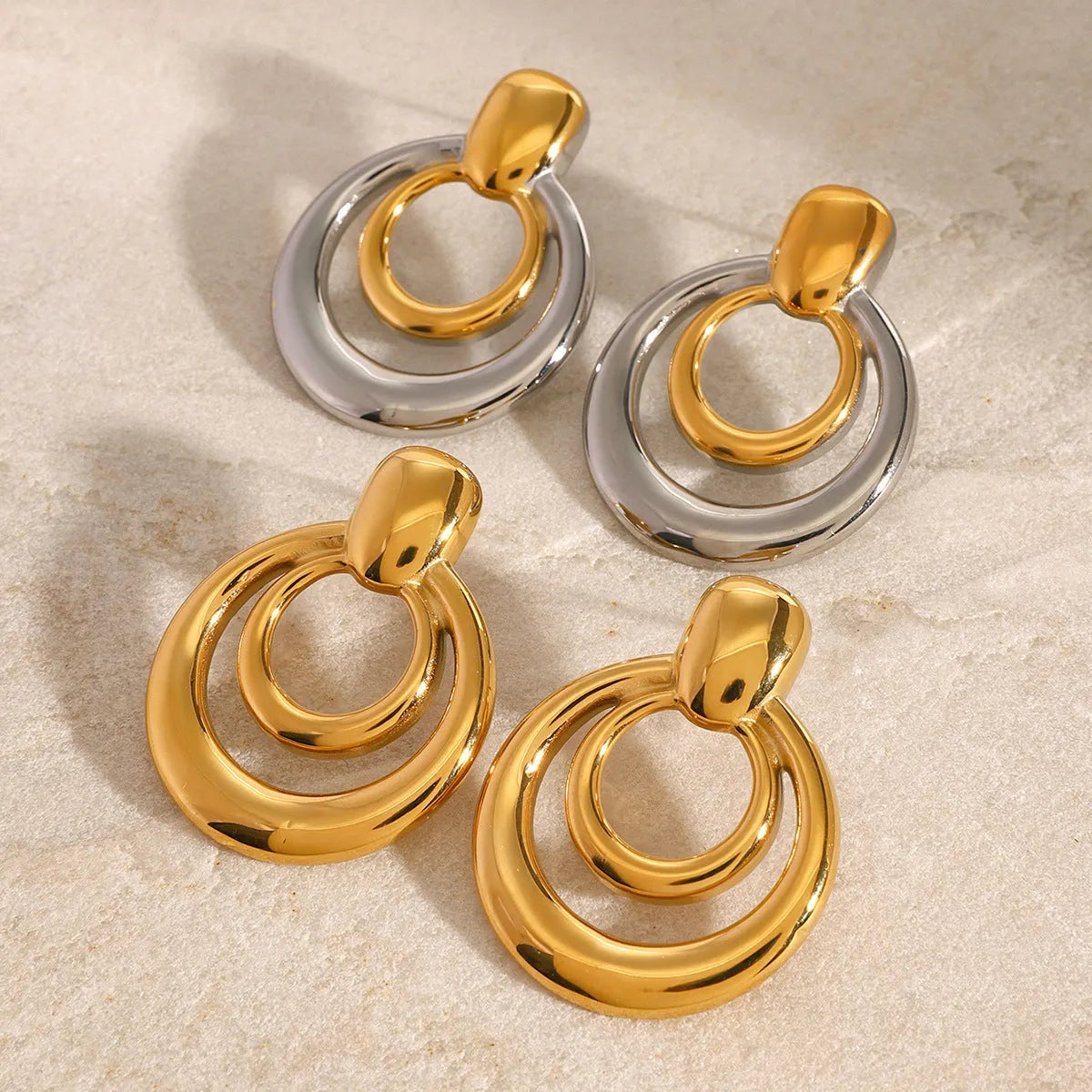 Round double layer hollow stud earrings with 18K gold electroplated finish on titanium steel