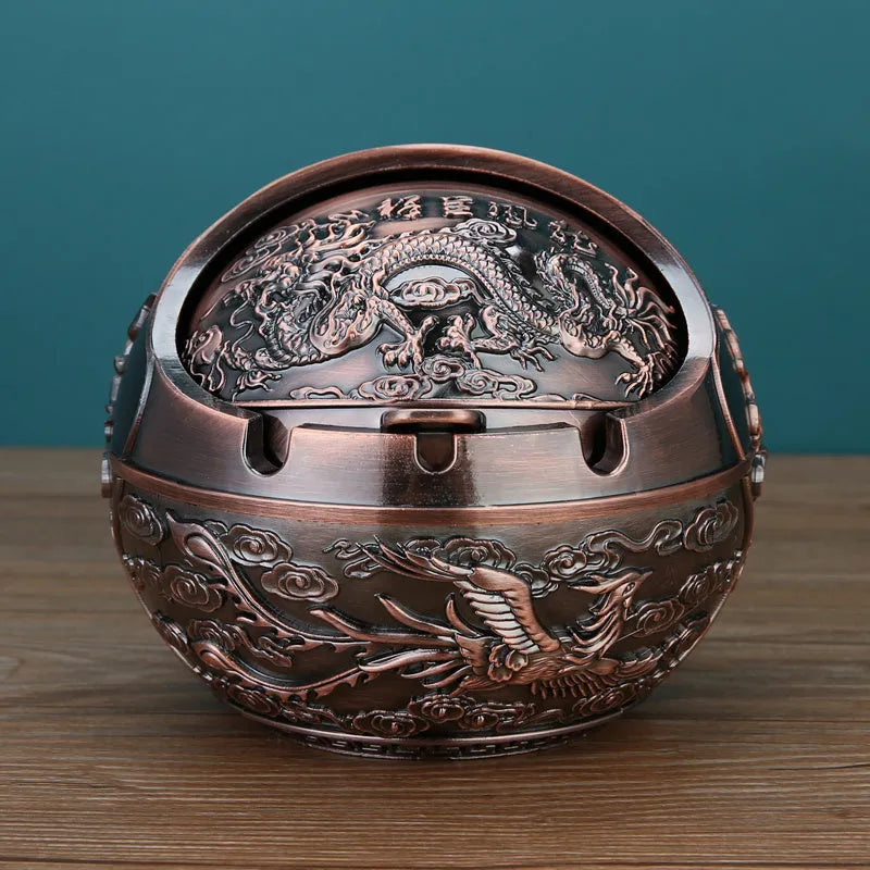 Bronze and red copper alloy decorative ashtray with smoke-extinguishing slot on a table.