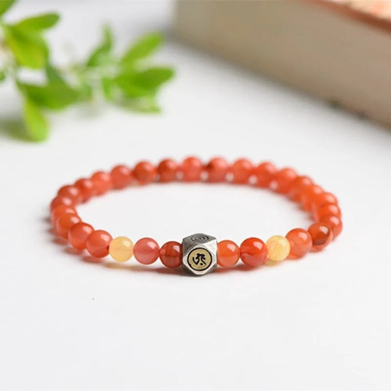 Natural red Nanhong agate zodiac bracelet with a yellow beeswax bead on a wrist.