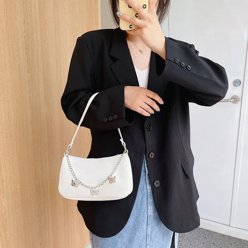 Retro-style light blue underarm shoulder bag with a silver butterfly chain strap, shown worn crossbody.