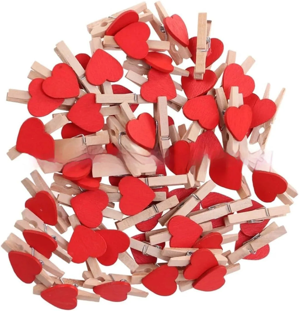 Set of five colourful handmade wooden heart-shaped clips in red, pink, white, and yellow on a wooden surface.