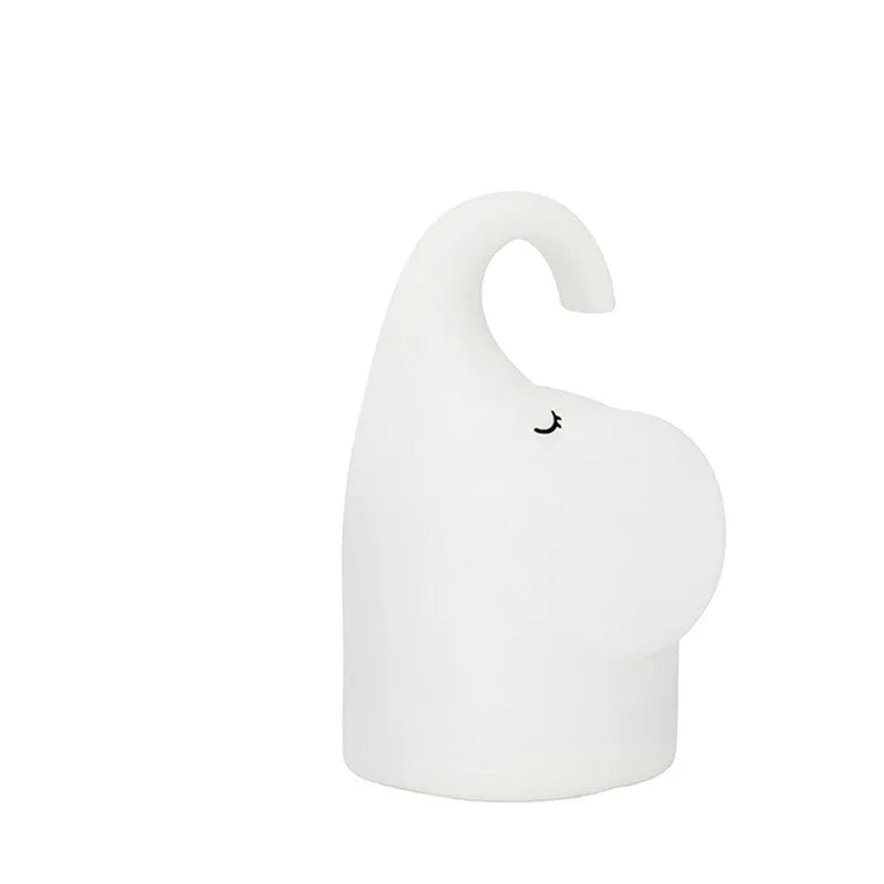 DOMI Elephant shaped silicone night light with warm white glow on a bedside table.