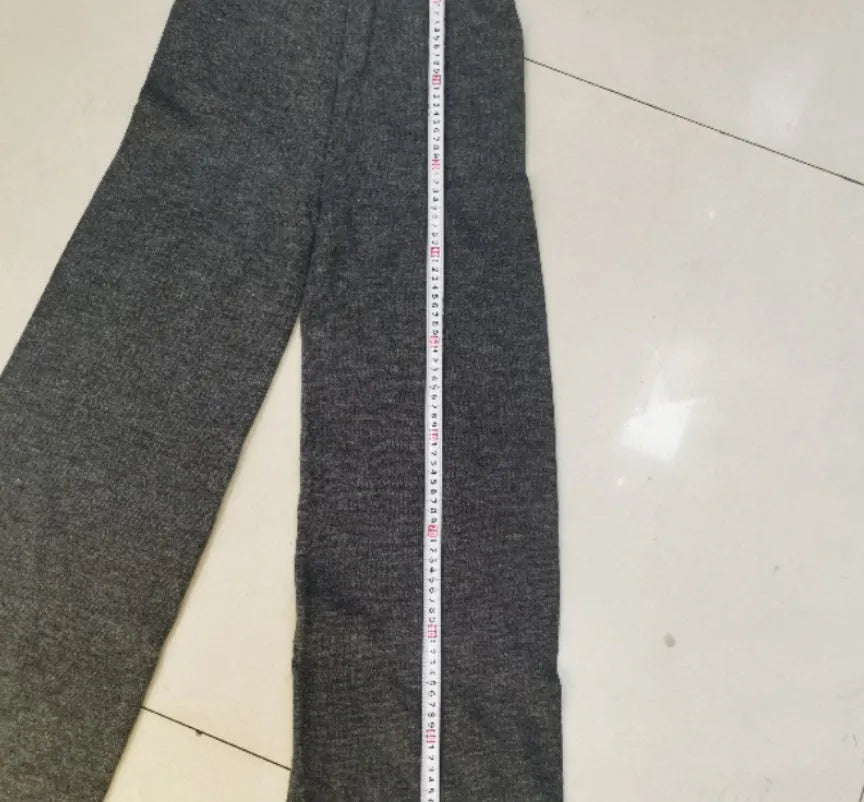 Women's dark grey acrylic sweater with side slits and matching full-length trousers laid flat.