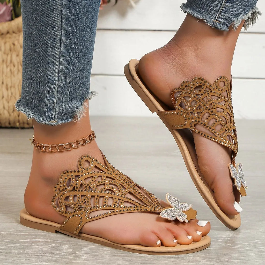Women's black slip-on sandals with rhinestone decoration on the toe, showing flip-toe and flat rubber sole design.
