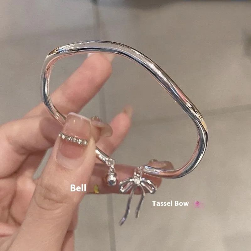 Silver adjustable bracelet with a detailed bow charm on a model's wrist, showing the adjustable clasp.