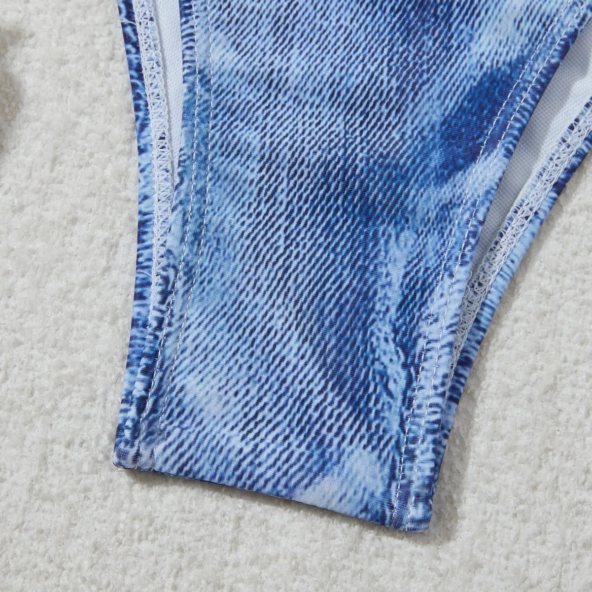 Denim blue printed women's two-piece bikini with thin straps, laid flat.