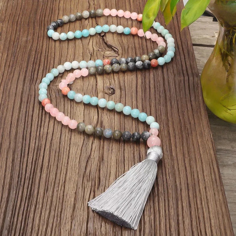 Bohemian style necklace and bracelet set with colourful drop-shaped stone pendants and tassel details on a white background