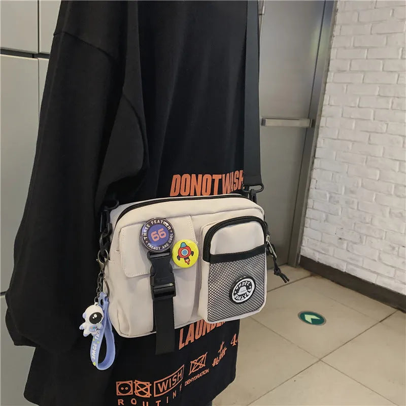 Casual nylon messenger bag for men and women, 22 x 6 x 17 cm, in black milky white grey or blue with two badge pendants