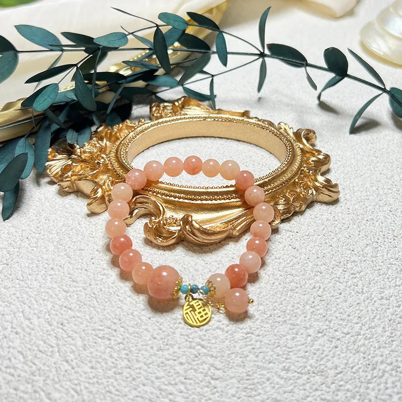 Pink alloy bracelet with natural stone details for women on a simple background.