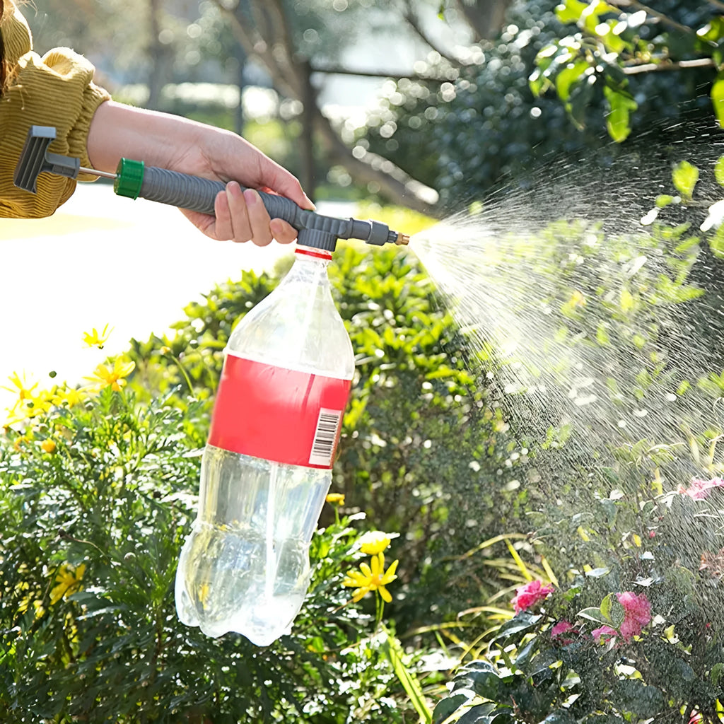 Plastic watering sprayer nozzle with extension tube attached to a large clear beverage bottle.
