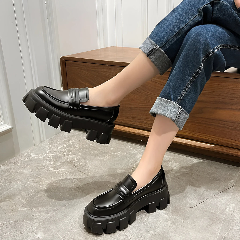 A pair of wide fit patent leather loafers with a flat rubber sole on a neutral background.
