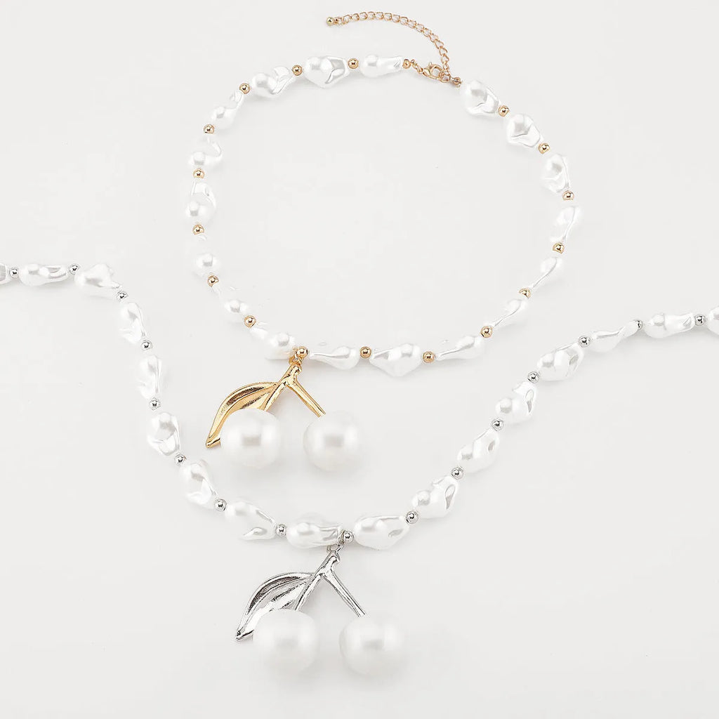 Gold irregular geometric cherry fruit pendant on an adjustable pearl chain necklace for women.
