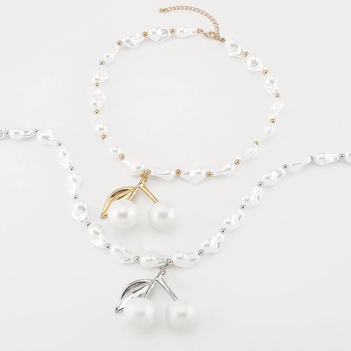 Gold irregular geometric cherry fruit pendant on an adjustable pearl chain necklace for women.