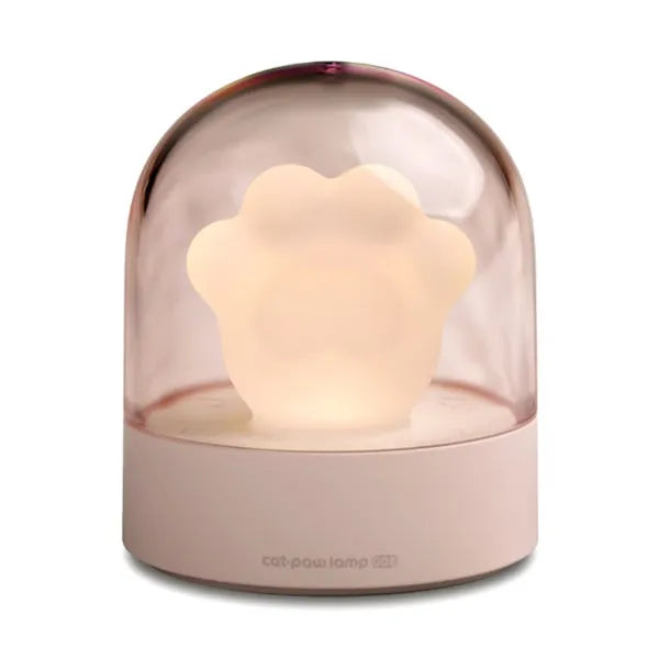 Pink cat paw shaped USB rechargeable night light with soft glow on a desk.