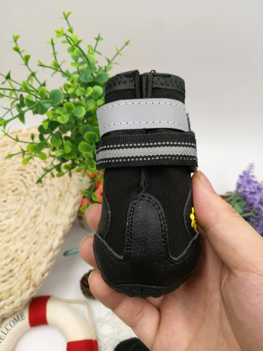Black pet dog shoes with waterproof PVC sole and adjustable fuzzy belt on a light background