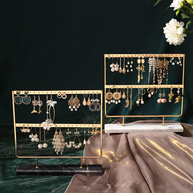 Alloy earring storage rack in green on a desktop holding multiple stud and hook earrings