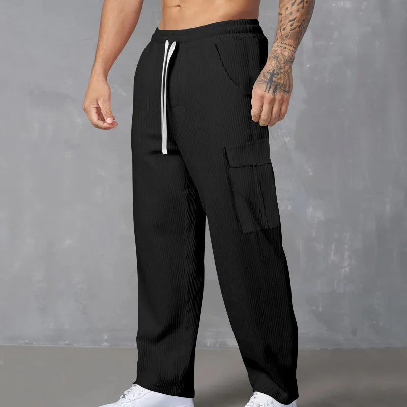 Man wearing navy blue loose-fit corduroy cargo trousers with a drawstring waist.