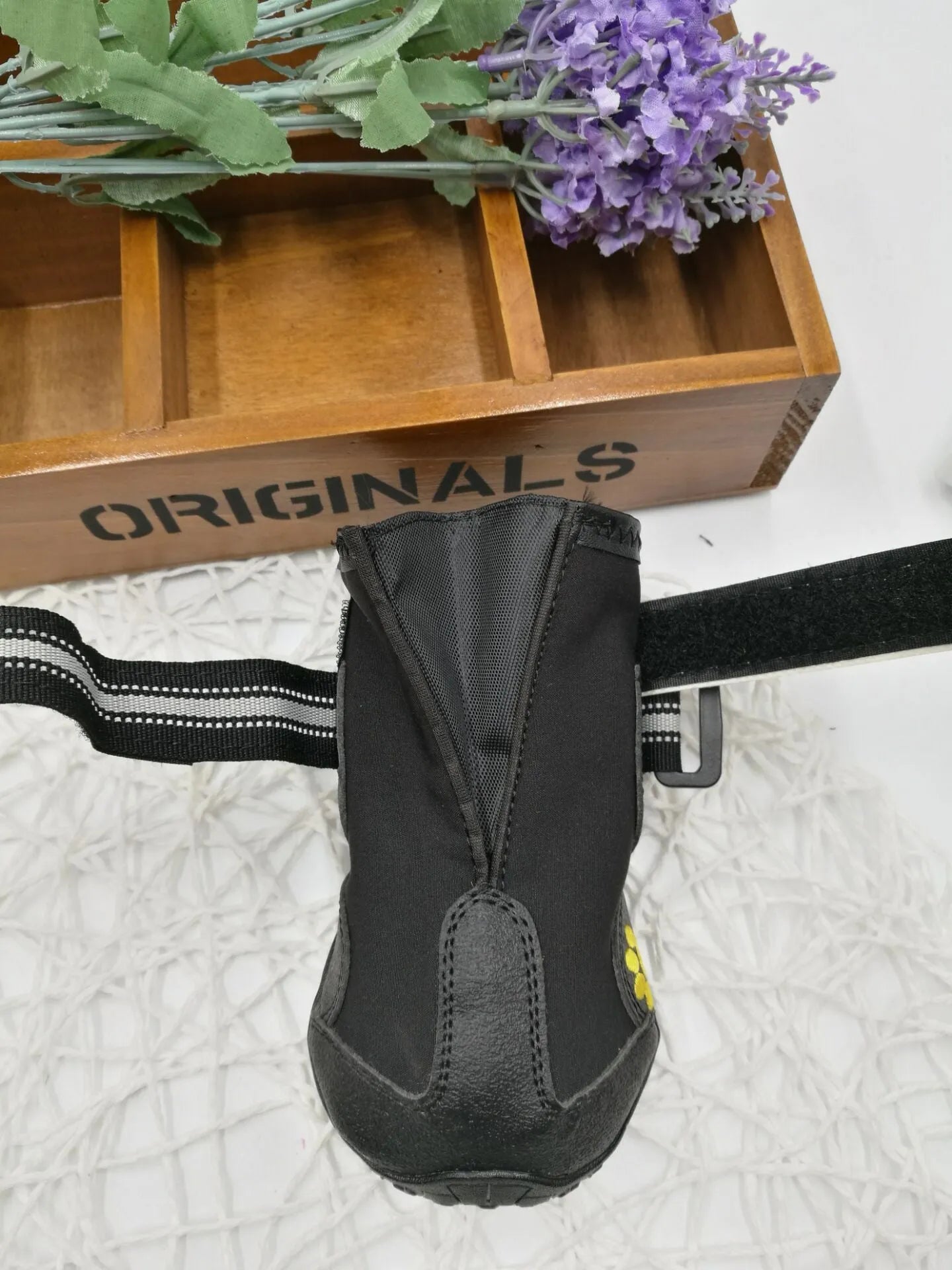 Black pet dog shoes with waterproof PVC sole and adjustable fuzzy belt on a light background