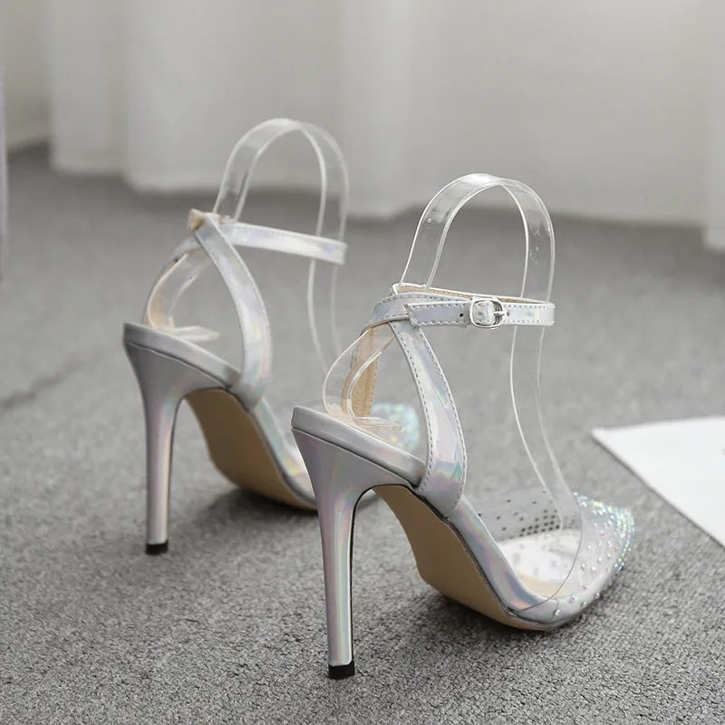 Clear PVC women's sandals with a pointed toe and a thin 10cm stiletto heel on a plain background.