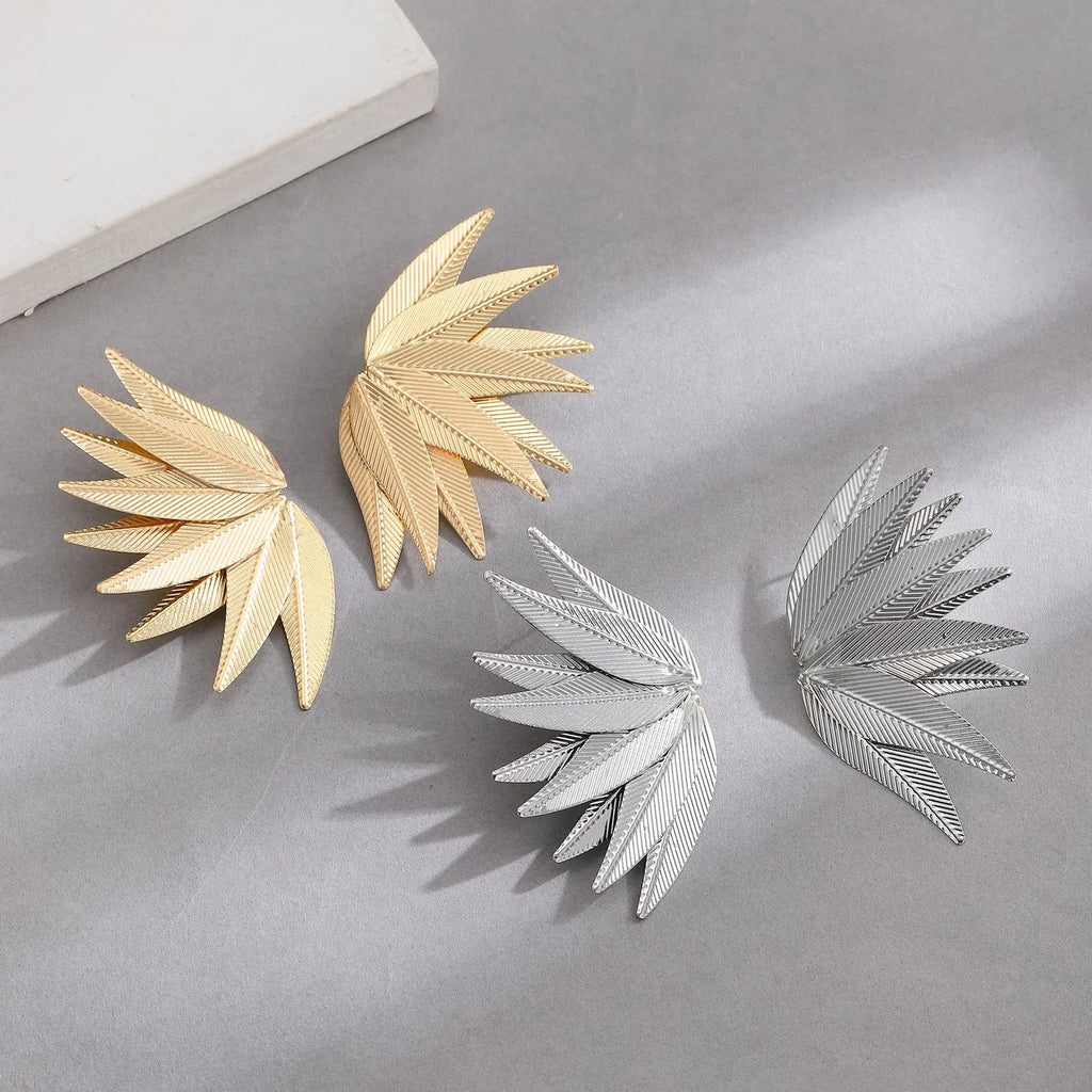 A pair of gold or white alloy earrings shaped like a leaf.