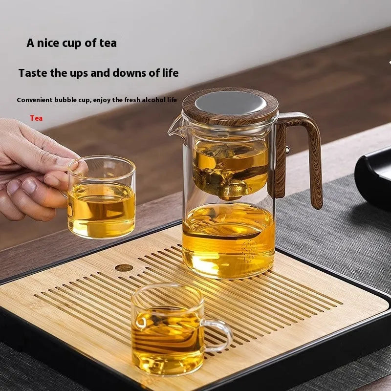 Glass teapot with wooden handle showing magnetic tea separation button and drip-free spout.