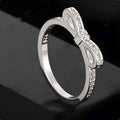 Silver coloured bow-shaped ring with sparkling rhinestone crystals on a model's hand.
