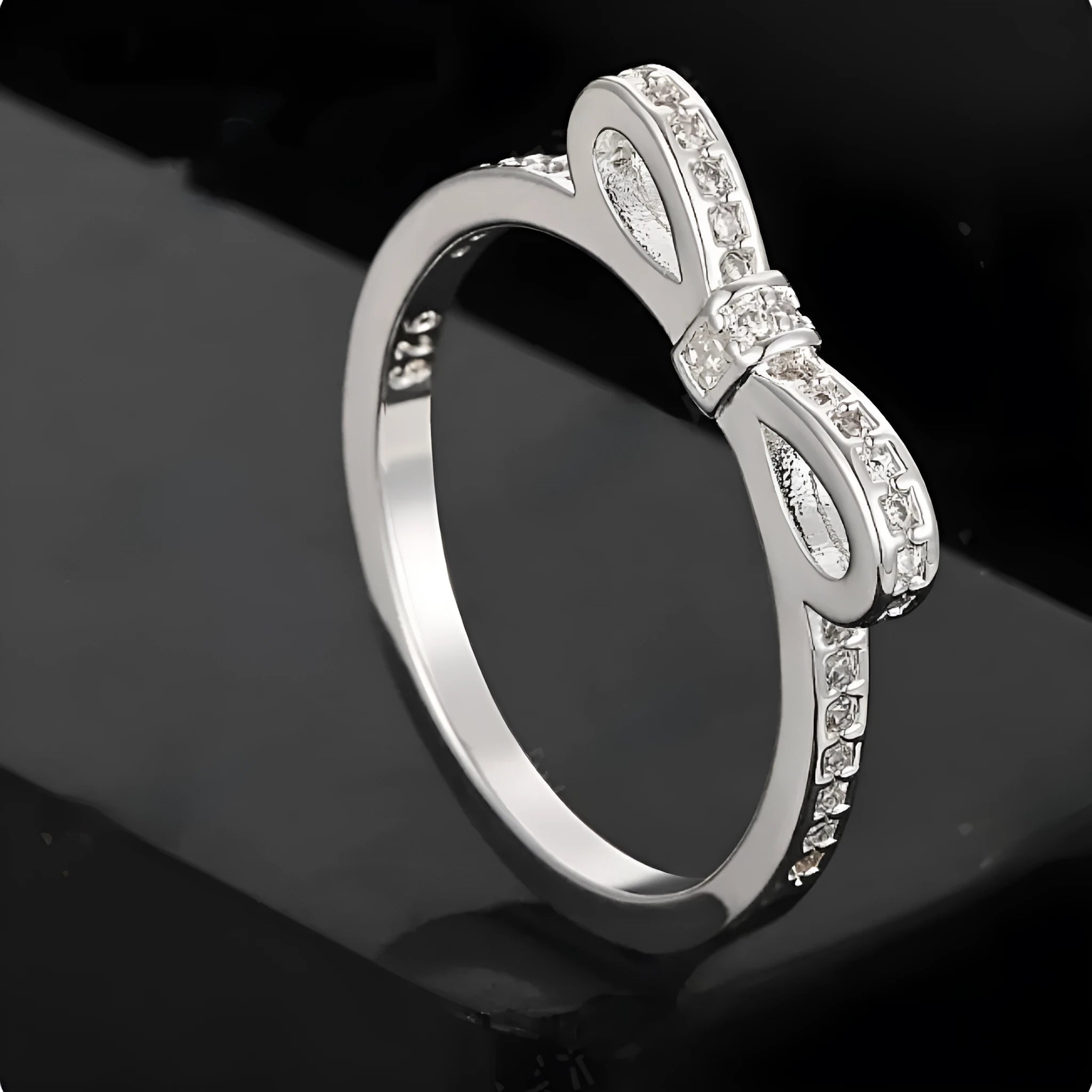 Silver coloured bow-shaped ring with sparkling rhinestone crystals on a model's hand.