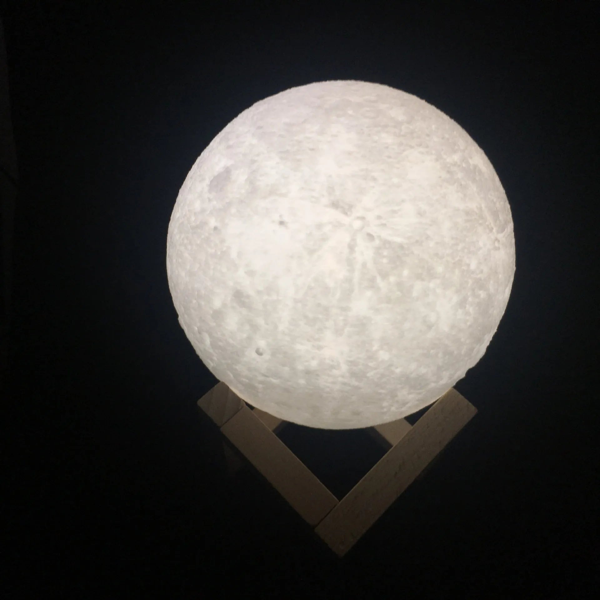 3D printed moon lamp on wooden stand showing detailed lunar surface, with touch ring at base.