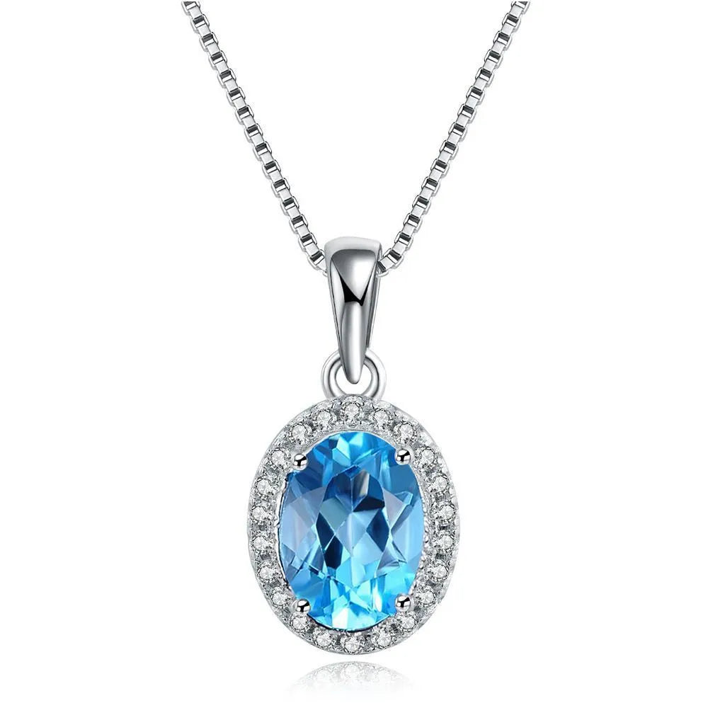 Four-piece sterling silver jewellery set with blue topaz gems: earrings, ring, pendant, and necklace on a geometry pattern.
