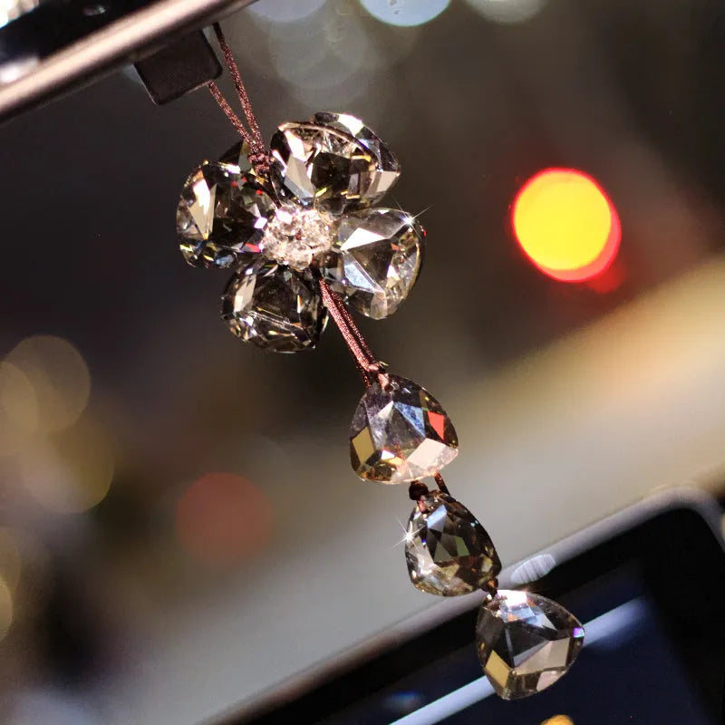 Crystal four leaf clover car pendant hanging, shown in one of four colour options: transparent, champagne, translucent black, or extremely shiny.