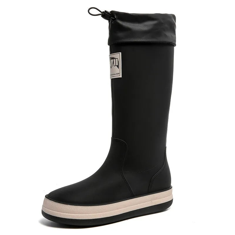 A pair of high tube PVC rain boots in a solid colour, shown on a size label with a non-slip sole.