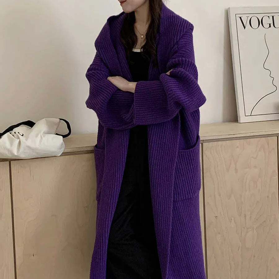 A woman wearing a long, loose, milky white hooded cardigan coat with raglan sleeves.