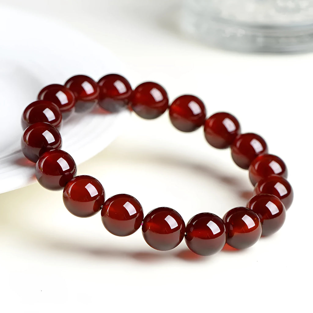Natural orange red garnet ball bracelet with crystal beads and Ruyi design on a wrist.