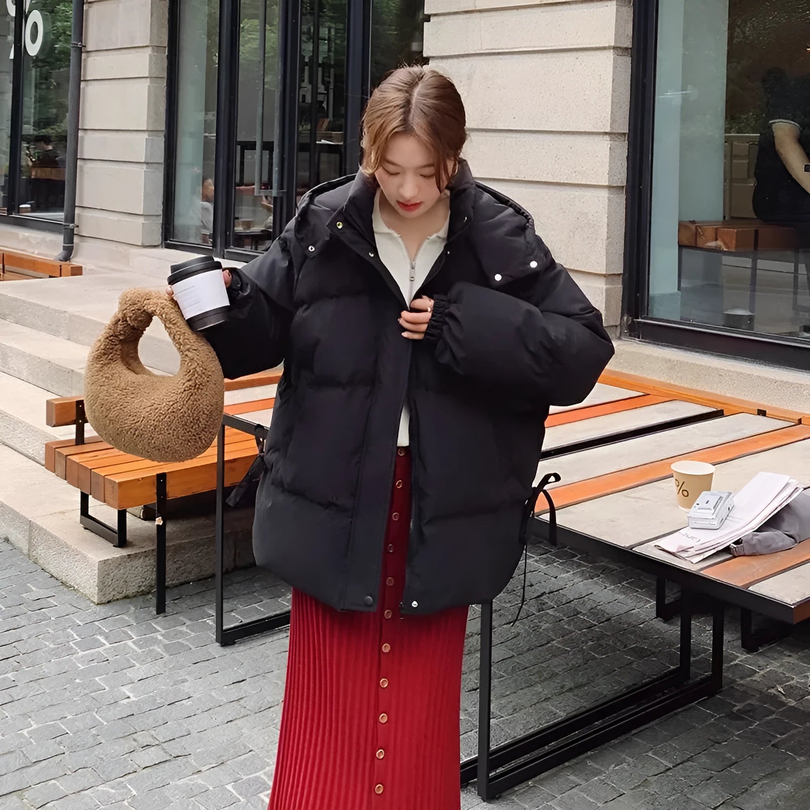 Women's loose black winter jacket with princess sleeves on a hanger.
