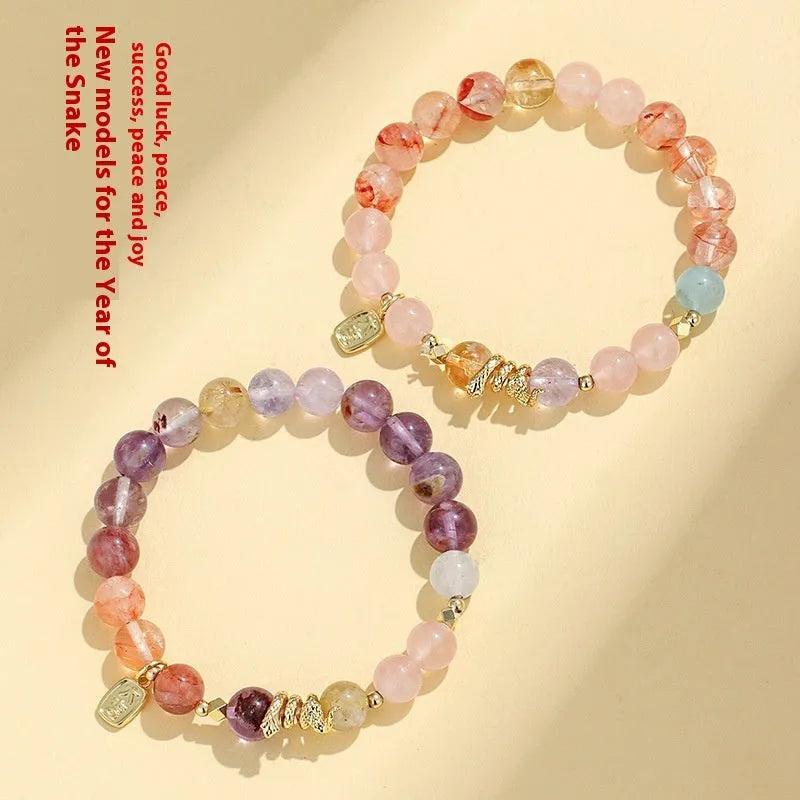 Handcrafted women's crystal bracelet with a lucky snake charm and red sealant flowers on a wrist.