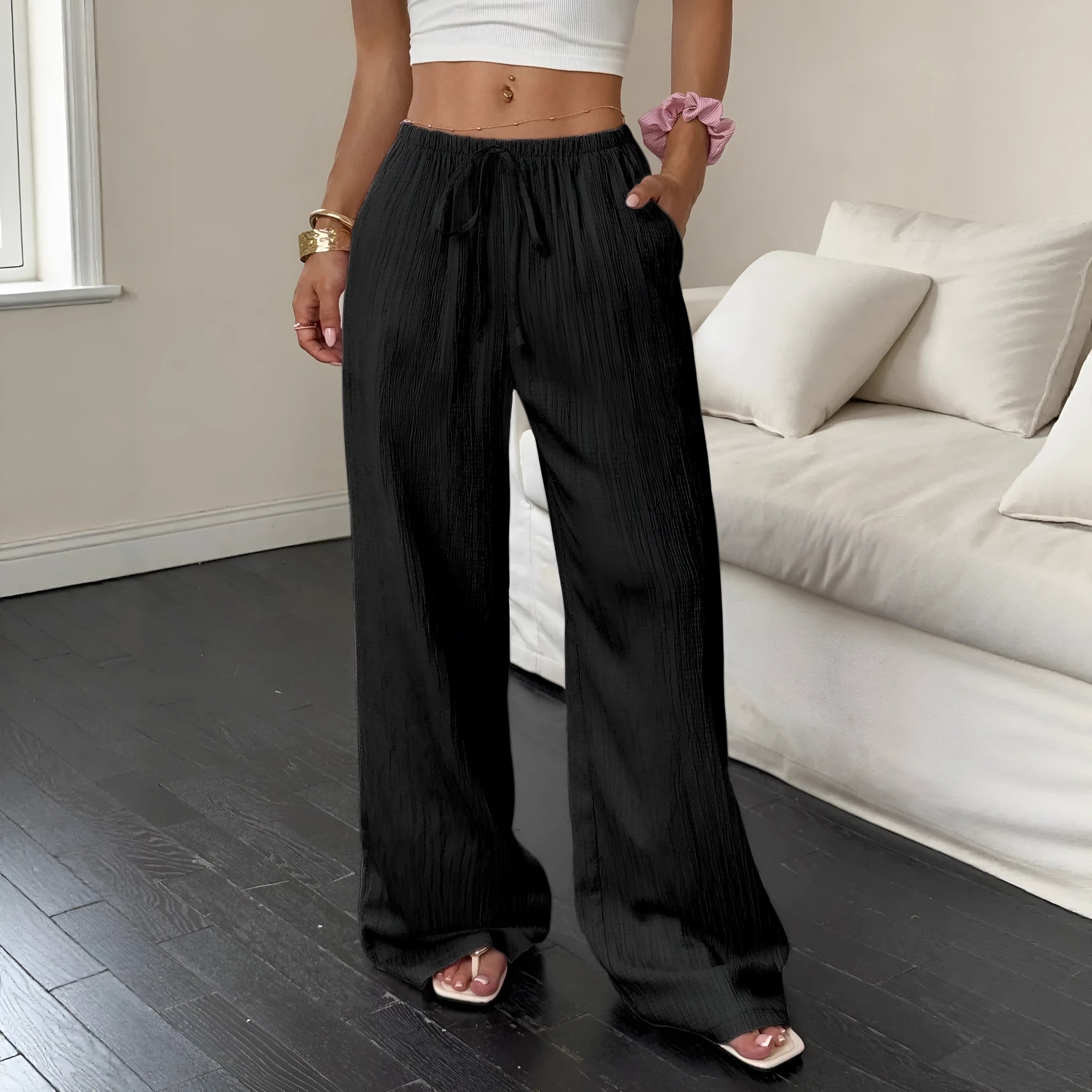 Women's black wide-leg trousers with a front lace-up waist detail on a neutral background.