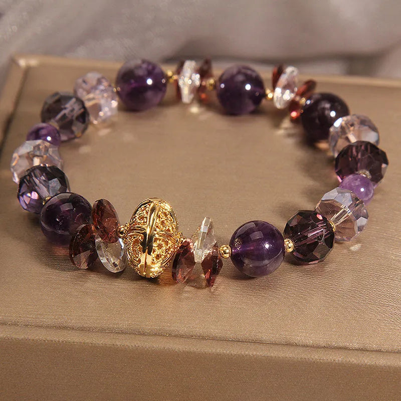 Purple crystal bracelet with pumpkin beads, wind chime charms, and rhinestone details on a wrist.