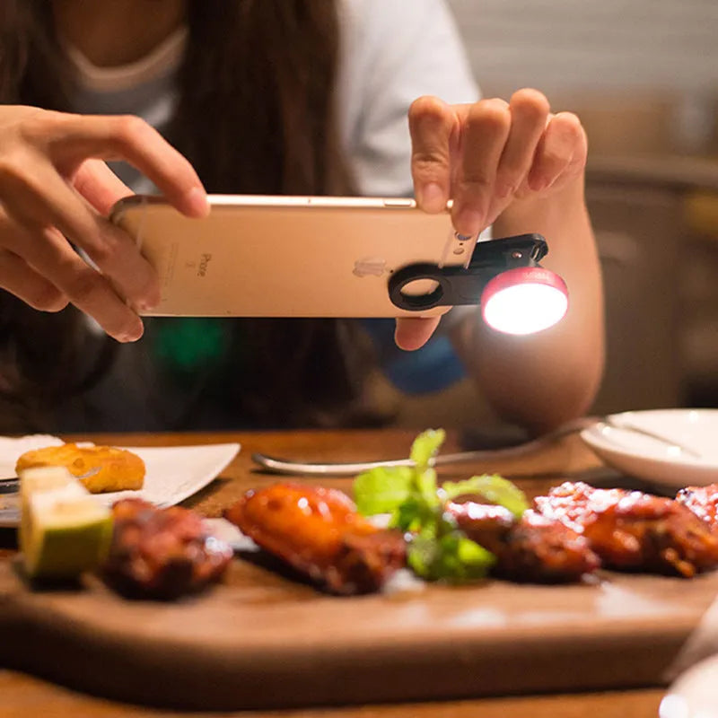 Universal smartphone camera lens kit with wide-angle and macro lenses, LED ring light, and mounting clip in black, red, or silver grey.