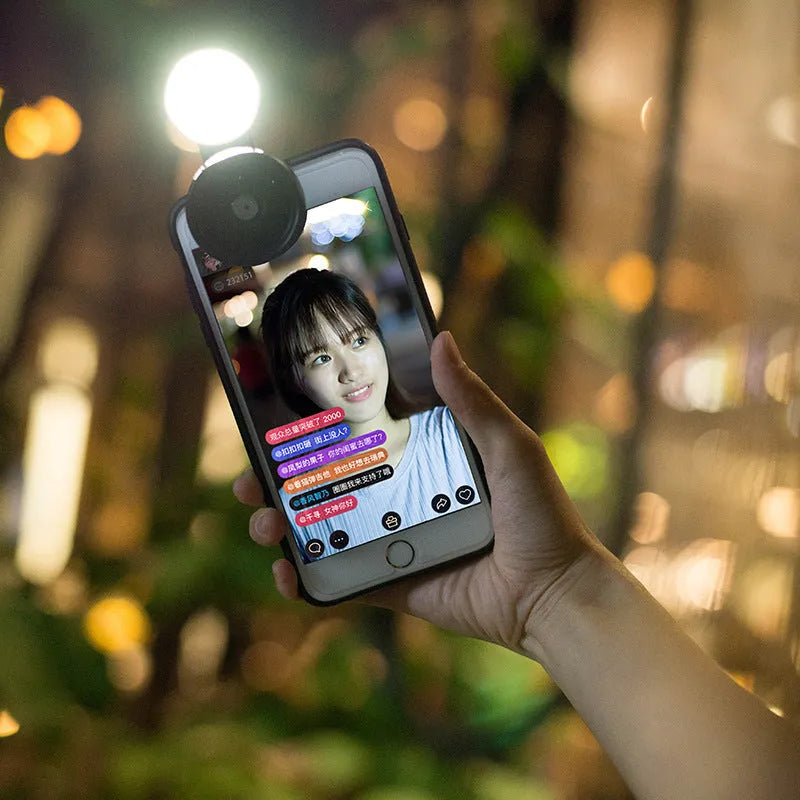 Universal smartphone camera lens kit with wide-angle and macro lenses, LED ring light, and mounting clip in black, red, or silver grey.