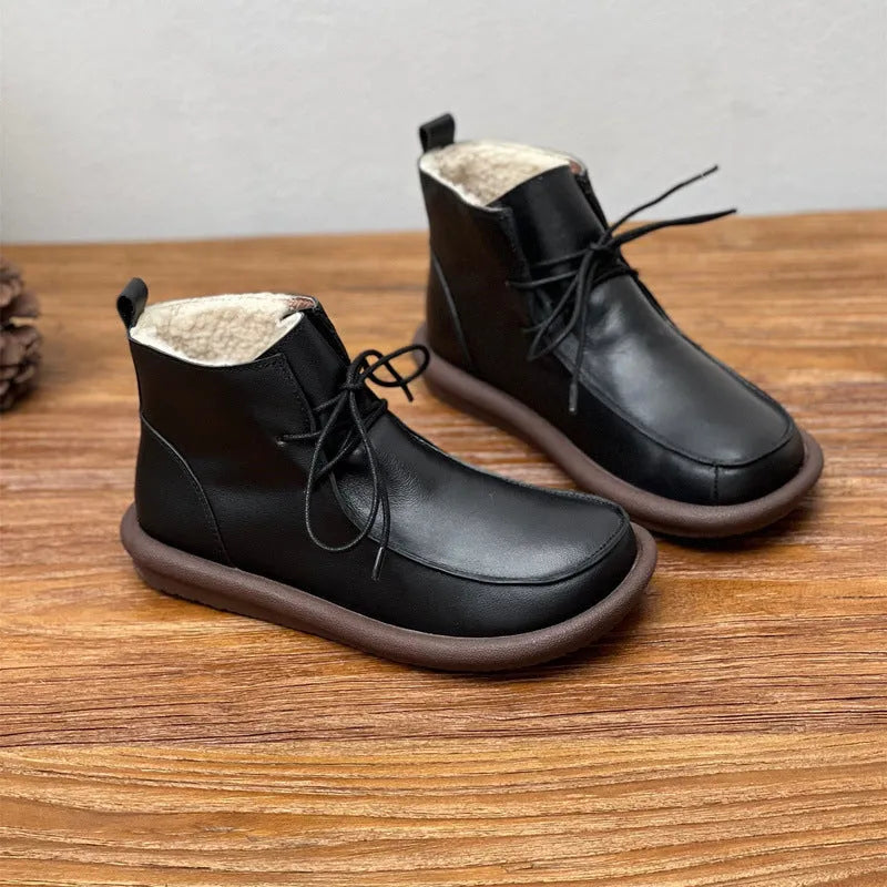 Women's black cowhide ankle boots with flat heel and round toe on a plain background