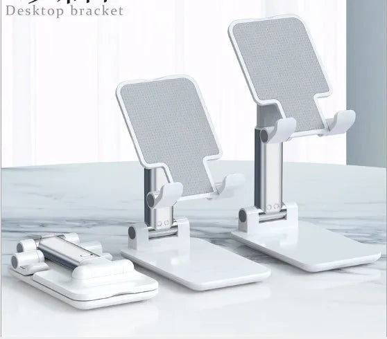 Black, white, green, and pink silicone and ABS plastic desk mobile phone holder on a wooden table.