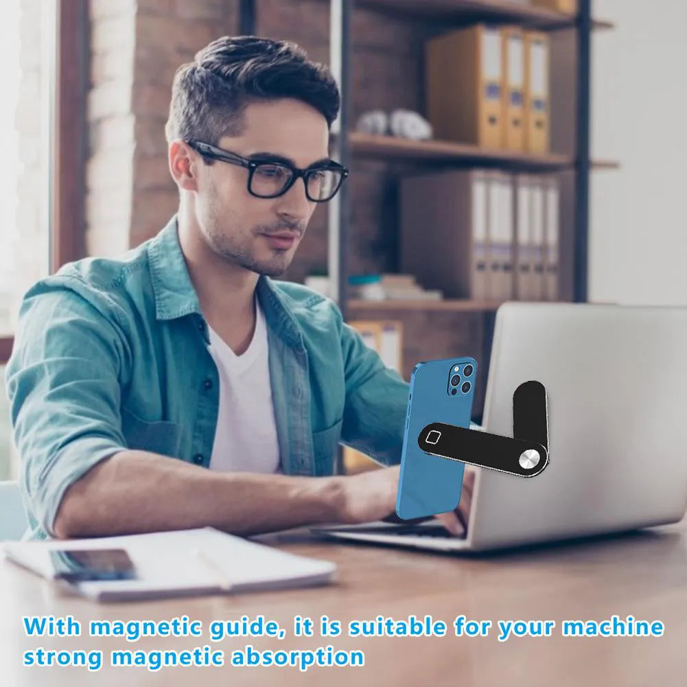 Black magnetic phone holder attached to side of silver laptop, showing phone mounted.
