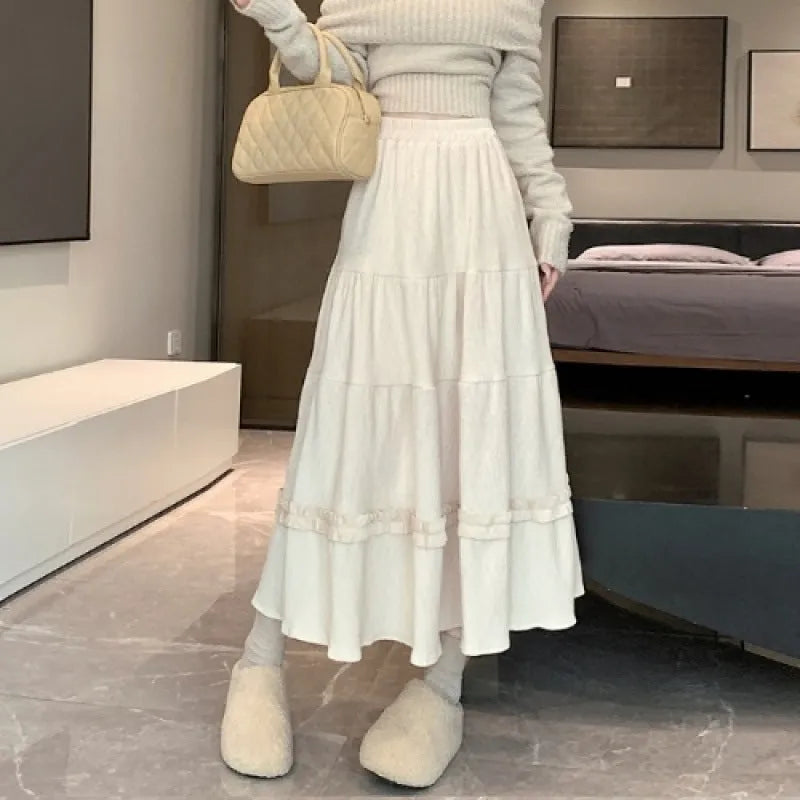 A woman modelling a beige corduroy midi A-line skirt with an elasticated waistband.
