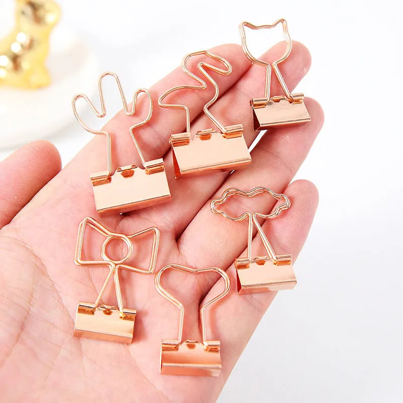 Gold metal long tail clip with a decorative bow charm on a white background.